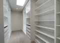 Cabinets by Durabella, of a large transitional gender-neutral light wood floor and brown floor walk-in closet design in San Francisco with open cabinets and white cabinets