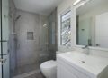 mid-sized transitional 3/4 gray tile and cement tile porcelain tile and gray floor bathroom design in San Francisco with flat-panel cabinets, white cabinets, a one-piece toilet, gray walls, an integrated sink, quartz countertops and a hinged shower door