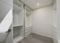 Inspiration for a mid-sized transitional gender-neutral medium tone wood floor and brown floor walk-in closet remodel in San Francisco with flat-panel cabinets and white cabinets